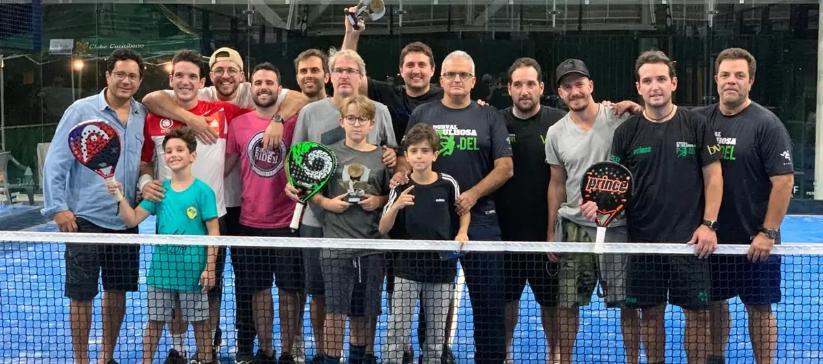 Grupo de jogadores reunido junto à rede, com crianças e adultos